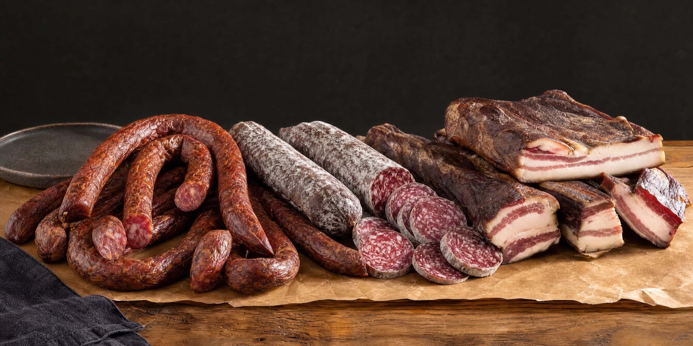 Smoked sausages, salami, and slănină spread across butcher paper