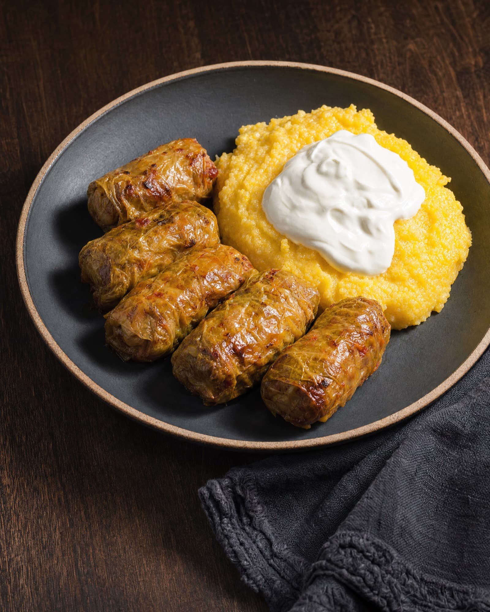 Sarmale with polenta and sour cream on a dark plate